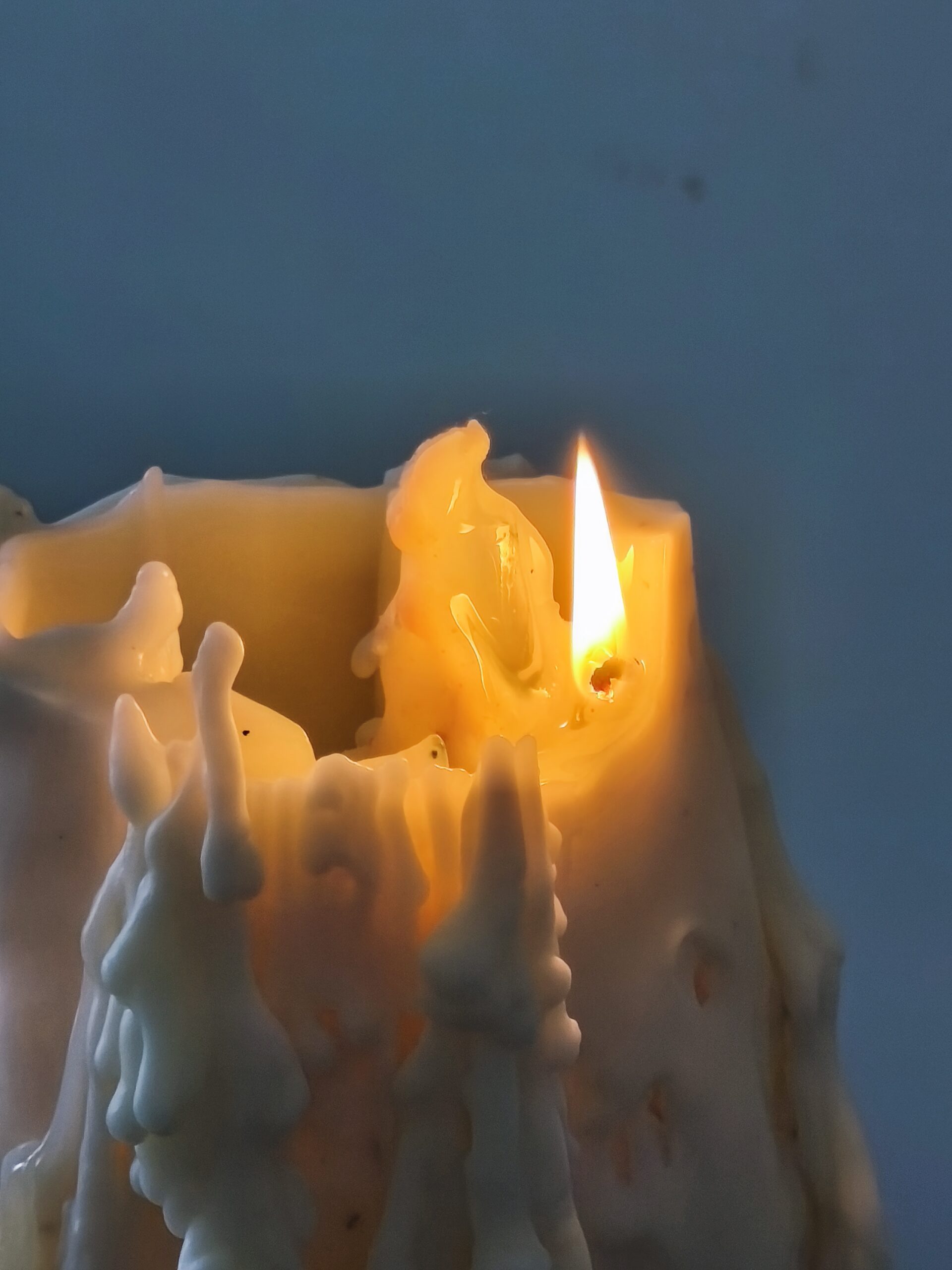 Sculpture lumineuse MÉORAH en combustion, révélant les reliefs et coulures de la cire.